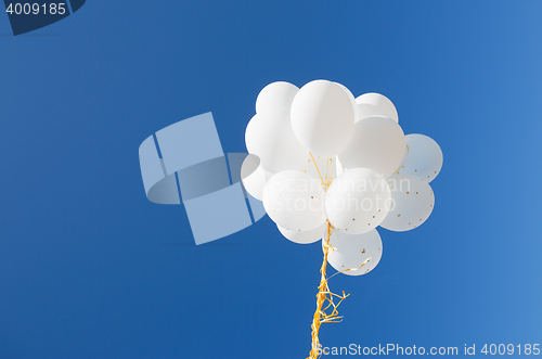 Image of close up of white helium balloons in blue sky