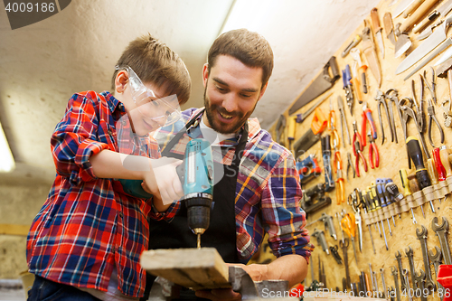 Image of father and son with drill working at workshop