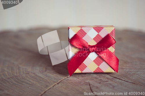 Image of Gift box with red bow on wood background