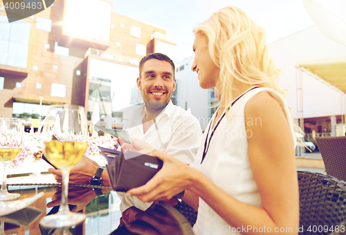 Image of happy couple with wallet paying bill at restaurant
