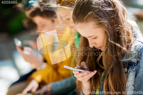 Image of happy teenage friends with smartphones outdoors