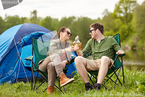 Image of happy couple clinking drinks at campsite tent
