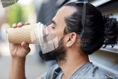 Image of man drinking coffee from paper cup on street