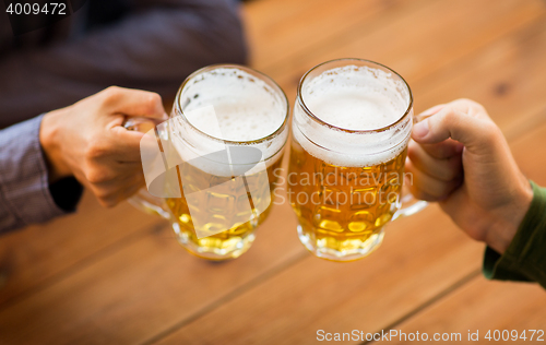 Image of close up of hands with beer mugs at bar or pub