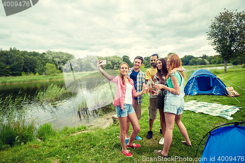 Image of happy friends taking selfie by smartphone at camp