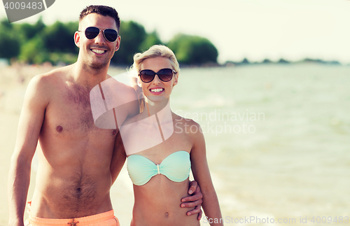 Image of happy couple in swimwear walking on summer beach