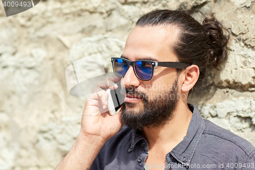 Image of smiling man with smartphone calling on city street