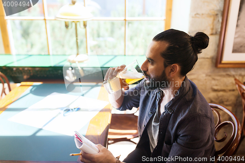 Image of man with notebook drinking beer at bar or pub