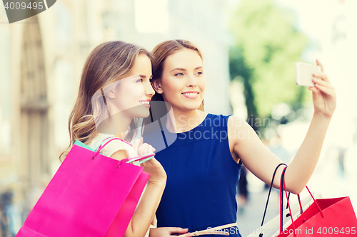 Image of happy women with shopping bags and smartphone