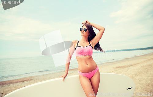 Image of smiling young woman with surfboard on beach