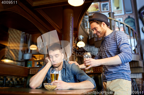 Image of man with beer and drunk friend at bar or pub