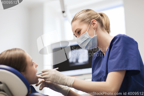 Image of female dentist checking patient girl teeth