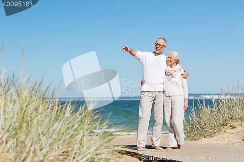 Image of happy senior couple hugging on summer beach