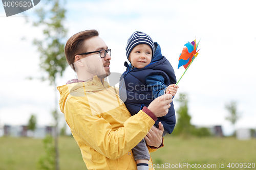 Image of happy father and son with pinwheel toy outdoors