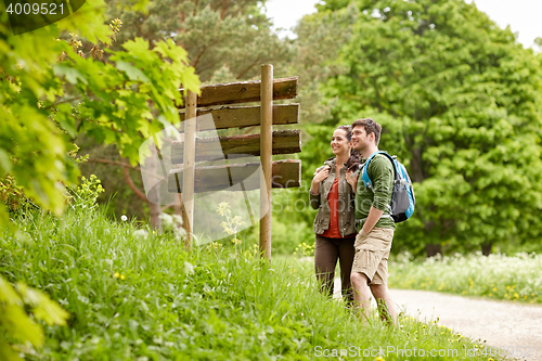 Image of smiling couple at signpost with backpacks hiking