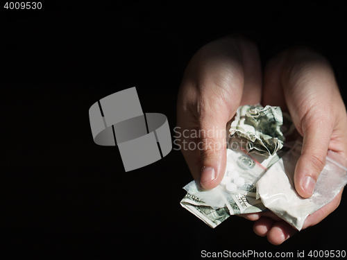 Image of close up of addict hands with drugs and money