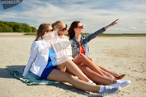 Image of group of smiling women in sunglasses on beach