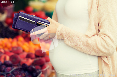 Image of pregnant woman with wallet buying food at market