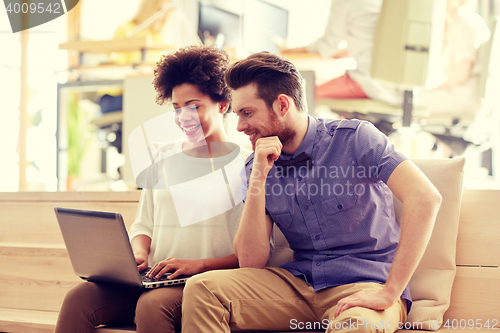 Image of happy creative team with laptop in office