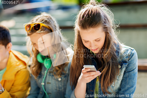 Image of happy teenage friends with smartphones outdoors
