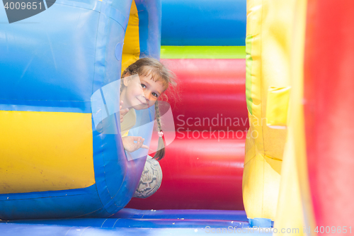 Image of Happy little girl got out of the inflatable soft barrel while playing on the trampoline