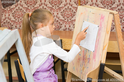 Image of Girl paints on an easel in the drawing lesson