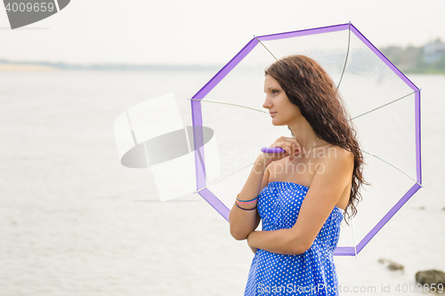 Image of Happy young girl standing with an umbrella on a background of a morning river