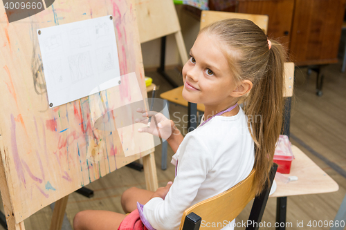 Image of Girl happily looks at the teacher at a drawing lesson