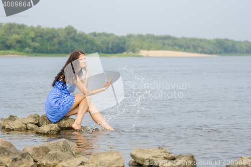 Image of Happy young girl sitting on the bank of the river enjoying condition comes summer