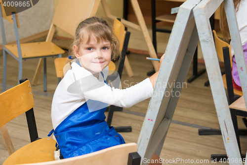 Image of Girl draws pencil on an easel to draw a lesson and looked into the frame