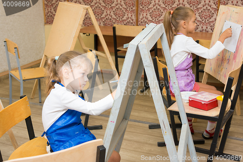 Image of Two girls at a drawing lesson paint on easels