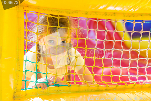 Image of A five-year girl is looking through a mesh trampoline inflatable