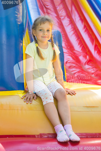 Image of Five-year girl sitting on a big inflatable trampoline