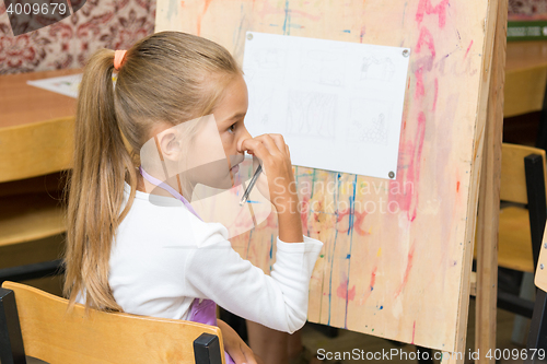 Image of Girl scratching nose listening to the teacher carefully at drawing lesson