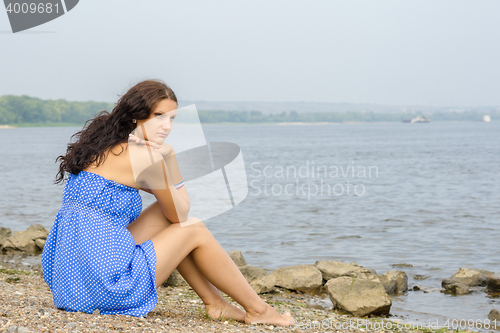 Image of Lonely sad young girl sitting on the river bank