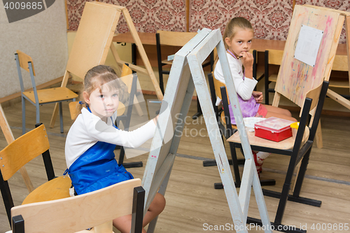 Image of Two girls at a drawing lesson listen to the teacher\'s explanations