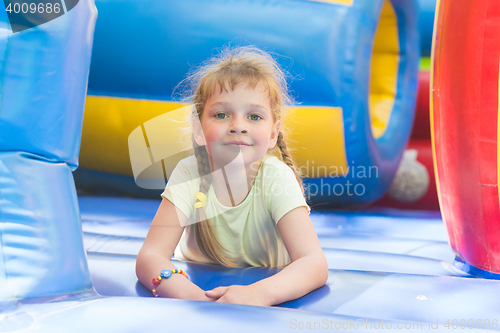 Image of Disheveled five year old girl is playing on a big inflatable trampoline