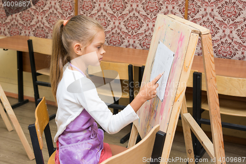 Image of Girl artist paints on an easel to draw circle