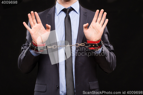 Image of man in a business suit with leather bound with handcuffs. sex Toys