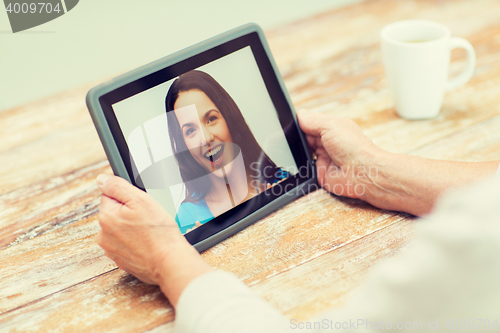 Image of senior woman with photo on tablet pc at home