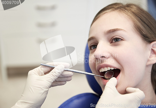 Image of hands with dental mirror checking girl teeth