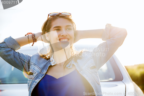Image of happy teenage girl or young woman near car
