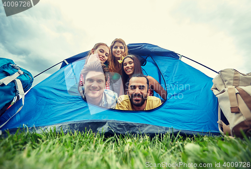 Image of happy friends with backpacks in tent at camping
