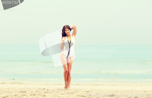 Image of young woman in swimsuit posing on beach