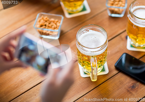 Image of close up of hands with smartphone picturing beer