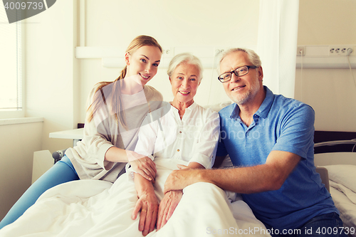 Image of happy family visiting senior woman at hospital