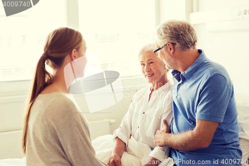 Image of happy family visiting senior woman at hospital