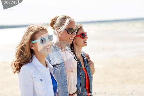 Image of group of smiling women in sunglasses on beach