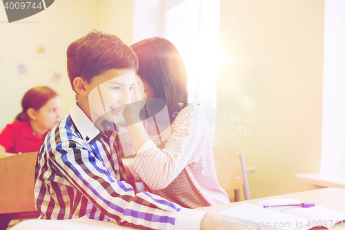 Image of smiling schoolgirl whispering to classmate ear