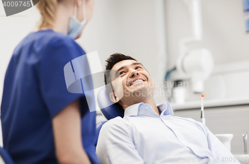 Image of female dentist with happy male patient at clinic